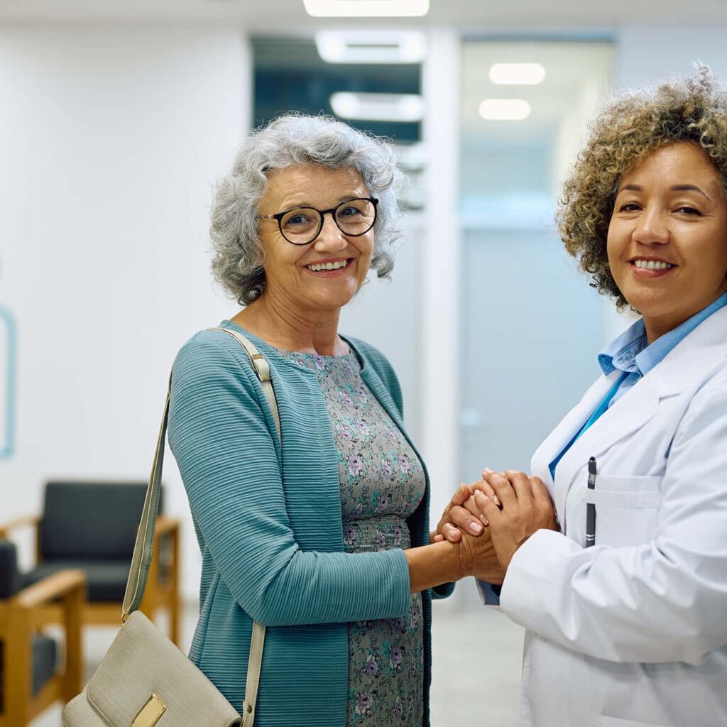 Smiling cancer survivor holding hands with female oncologist at CurePoint Cancer Center